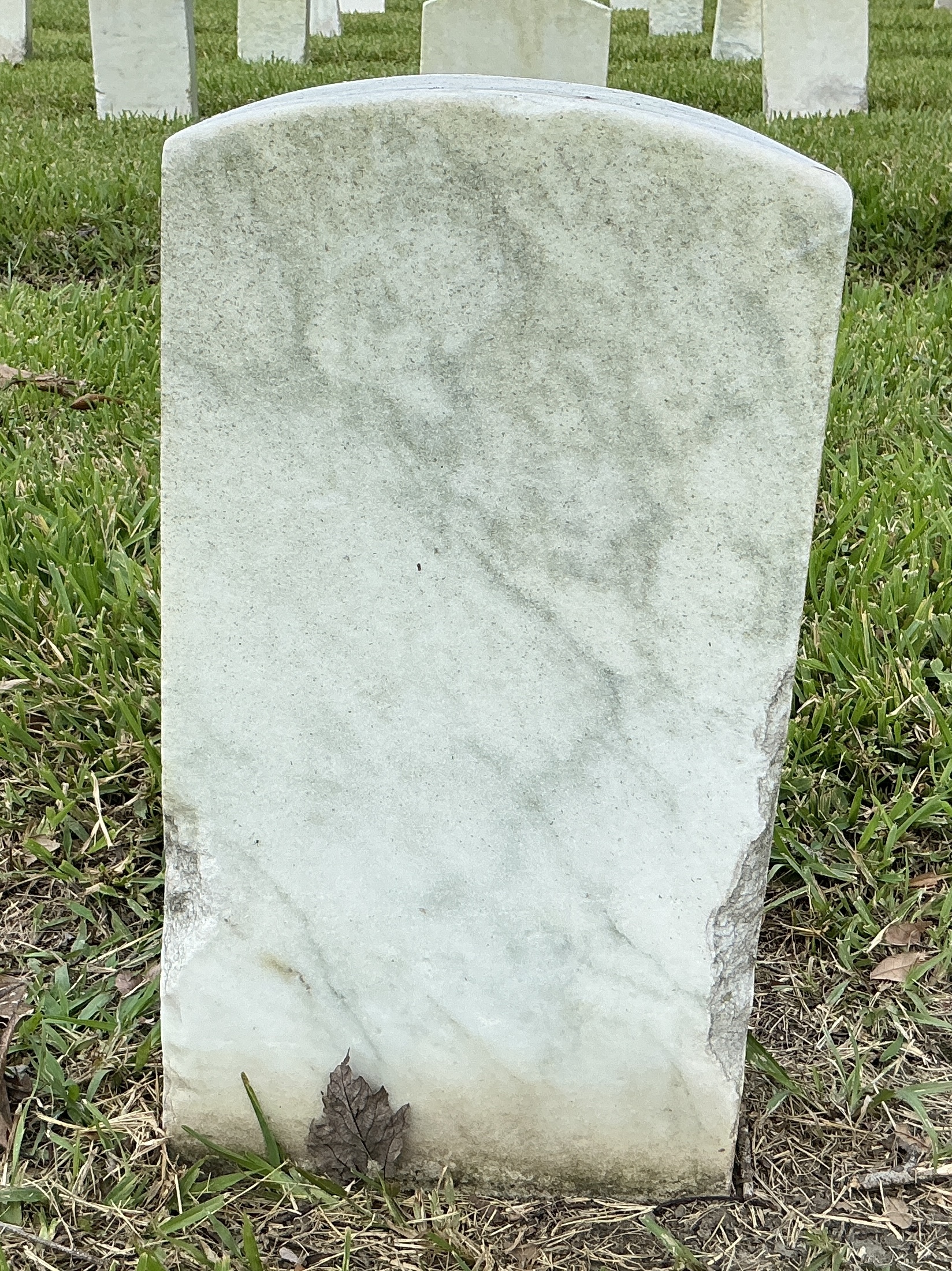 Back of historic upright marble headstone with recessed shield face.