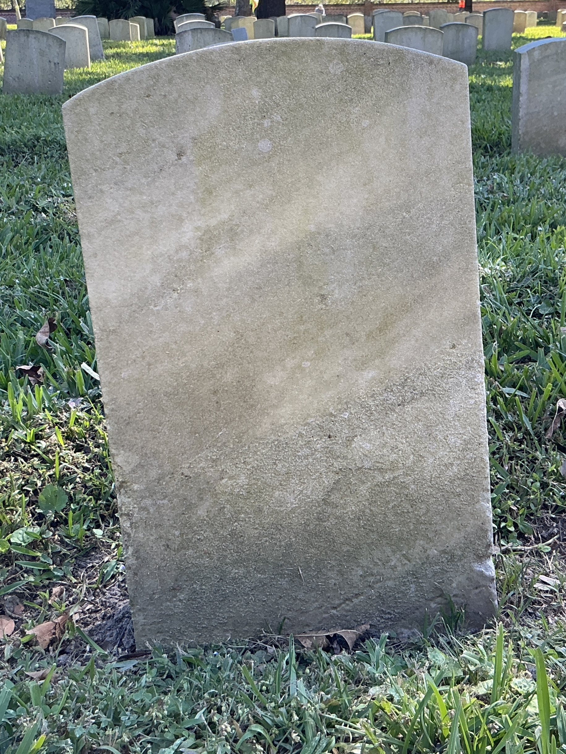 Back of historic upright marble headstone with recessed shield face.