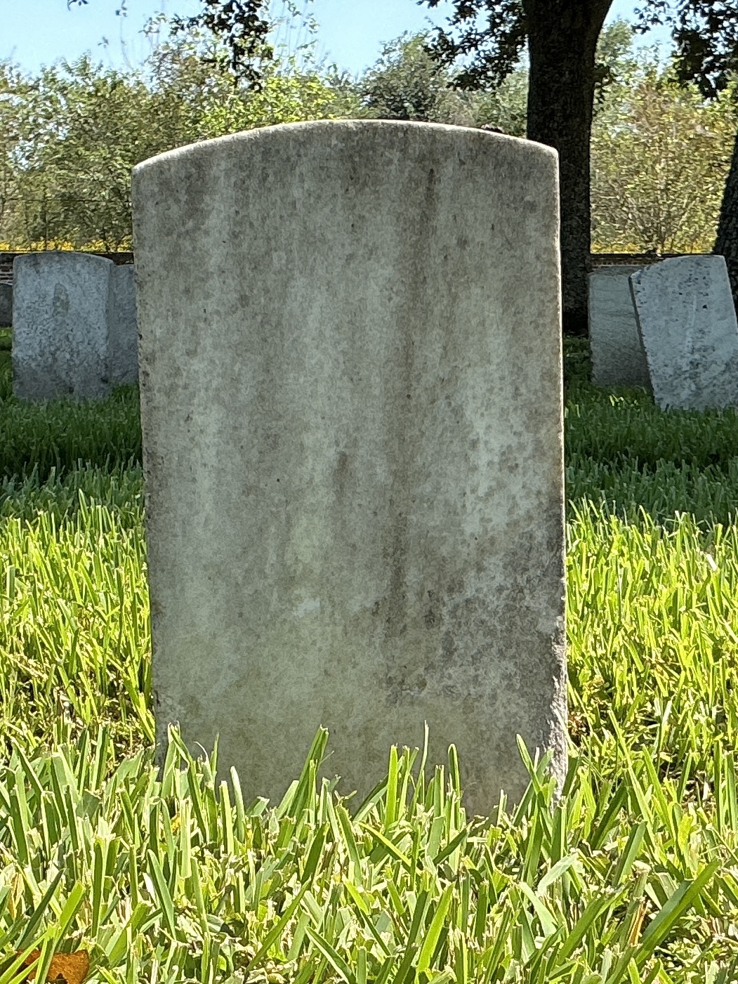 Back of historic upright marble headstone with recessed shield face.