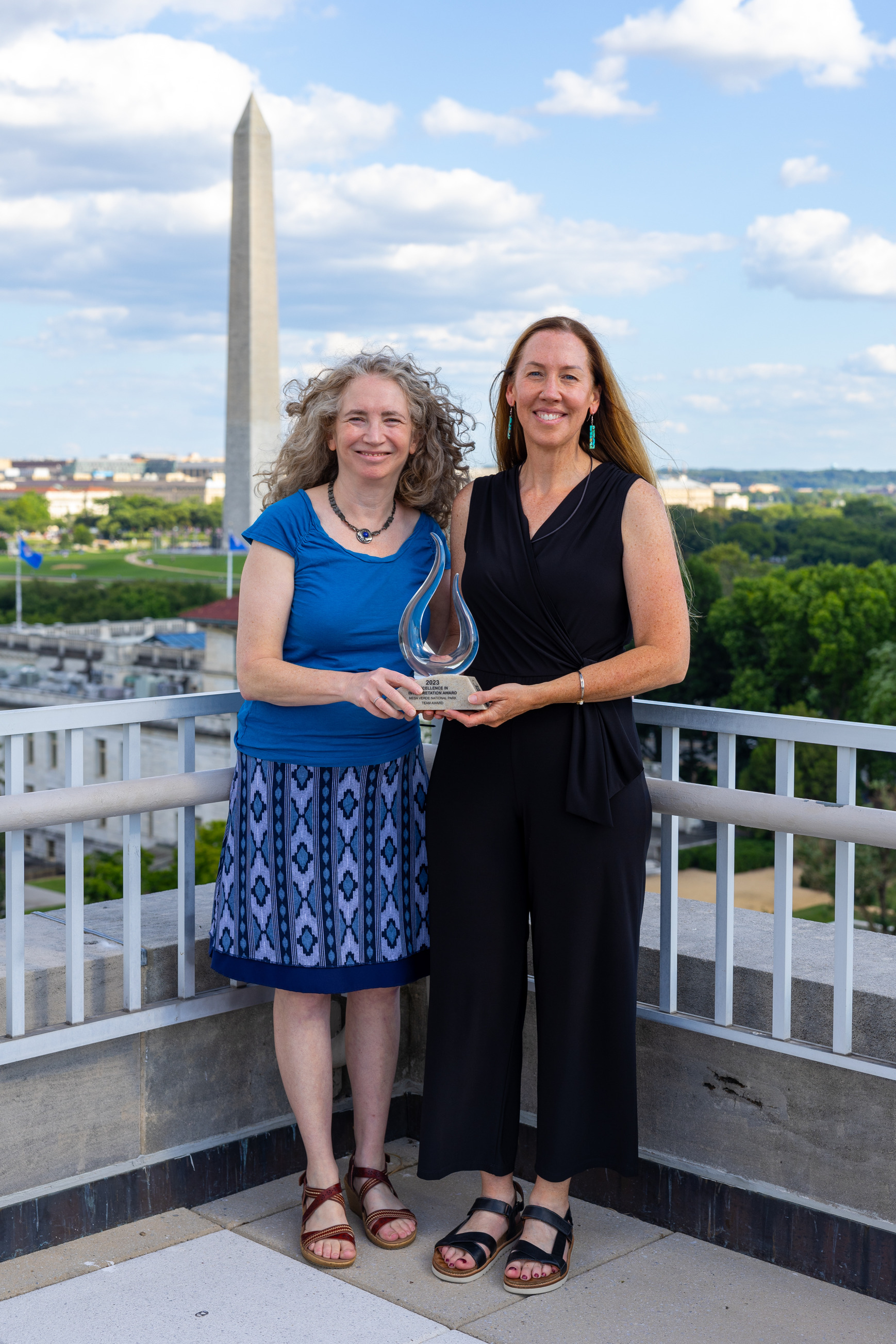 Two women holding an award on a rooftop