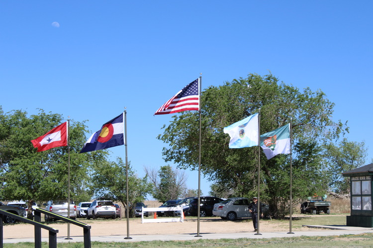 Five flags flying in front of trees.
