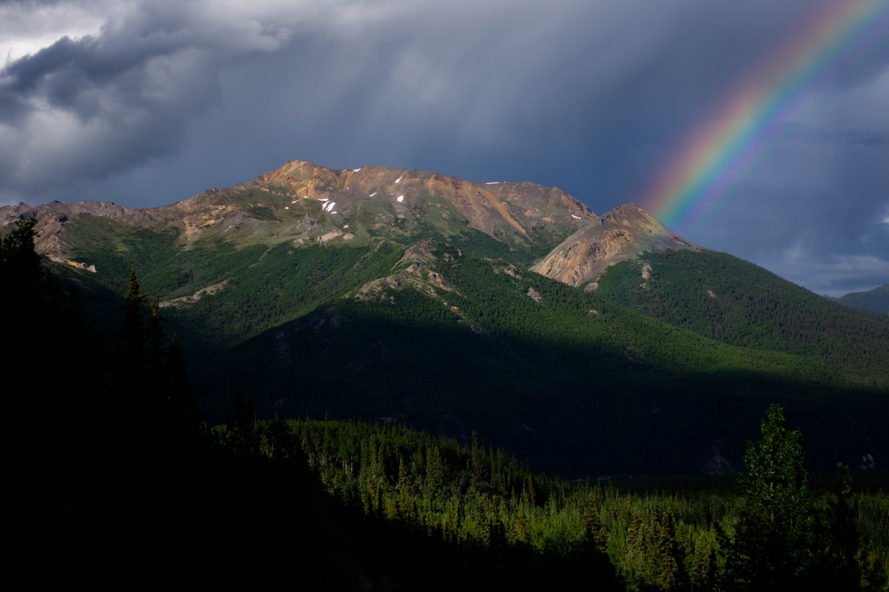 a rainbow over a mountain and forested valley