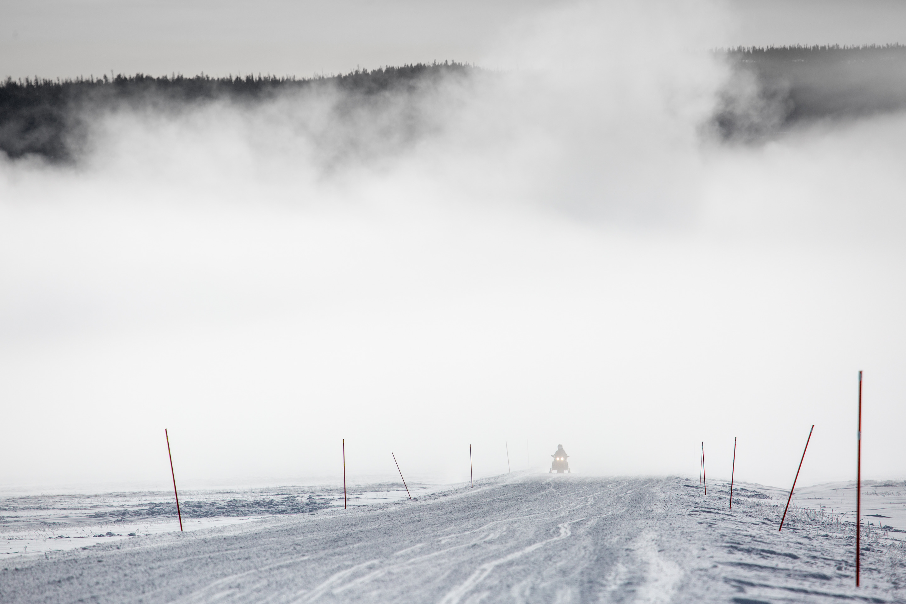 One snowmobiler riding through mist from the steam of the geyser basins