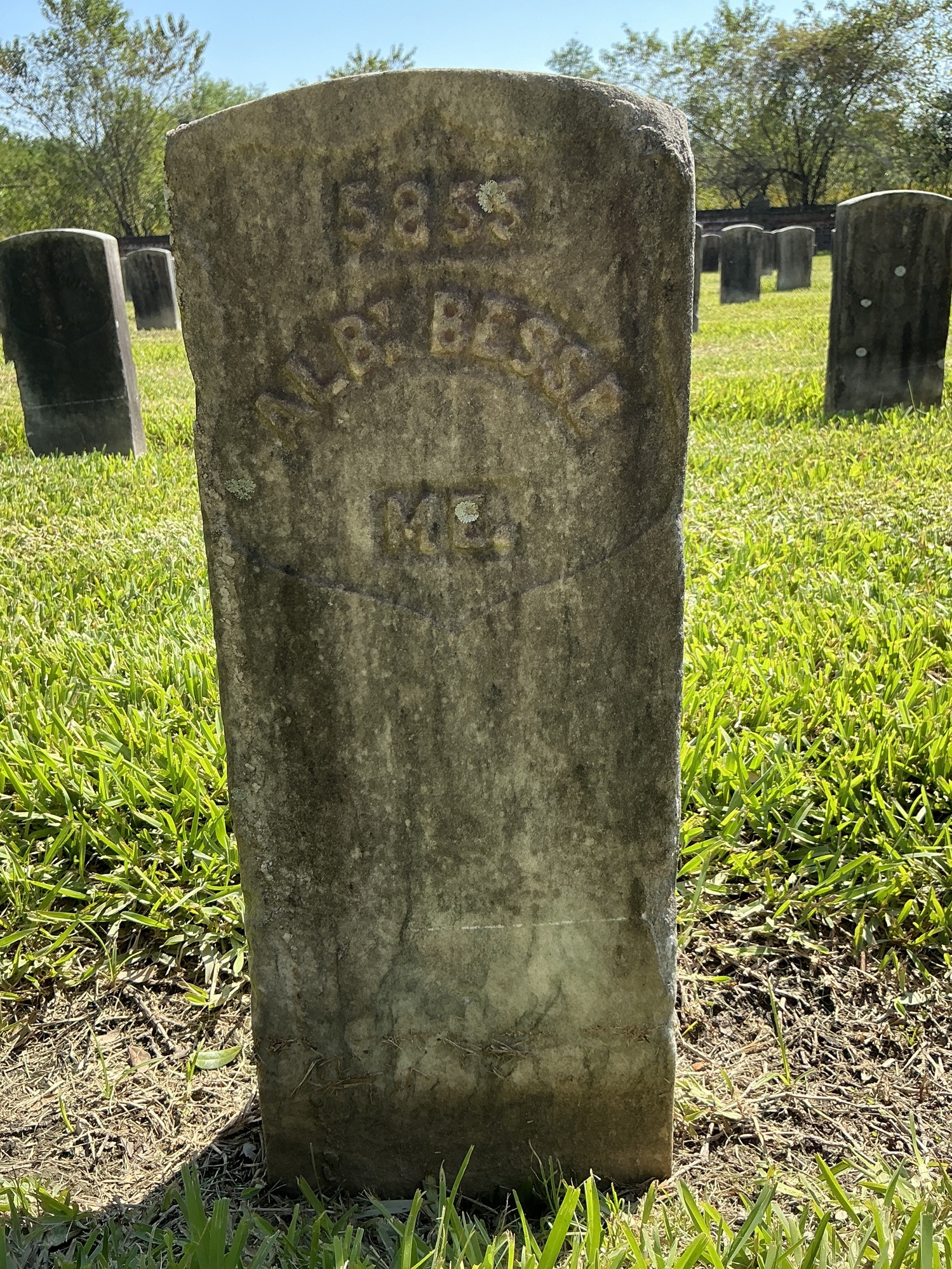 Front of historic upright marble headstone with recessed shield with recessed lettering face.