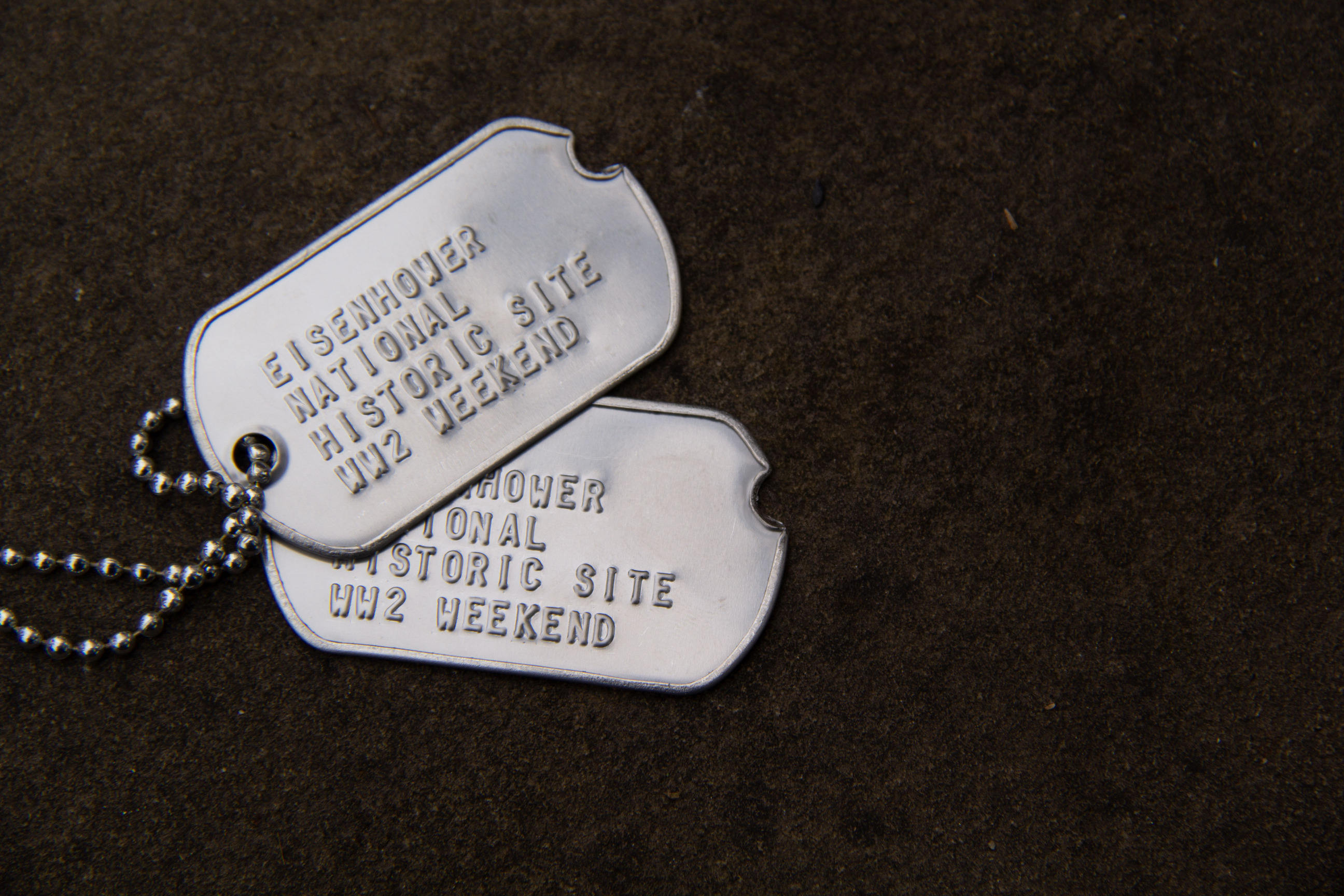 Two metal dog tags read “Eisenhower National Historic Site WW2 Weekend” 