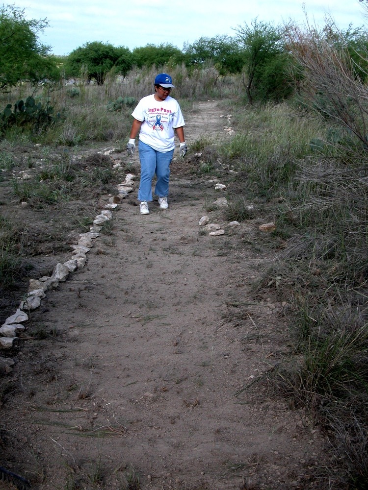 A volunteer from Southwest Texas Junior College edges a completed portion of the Sunrise Trail.