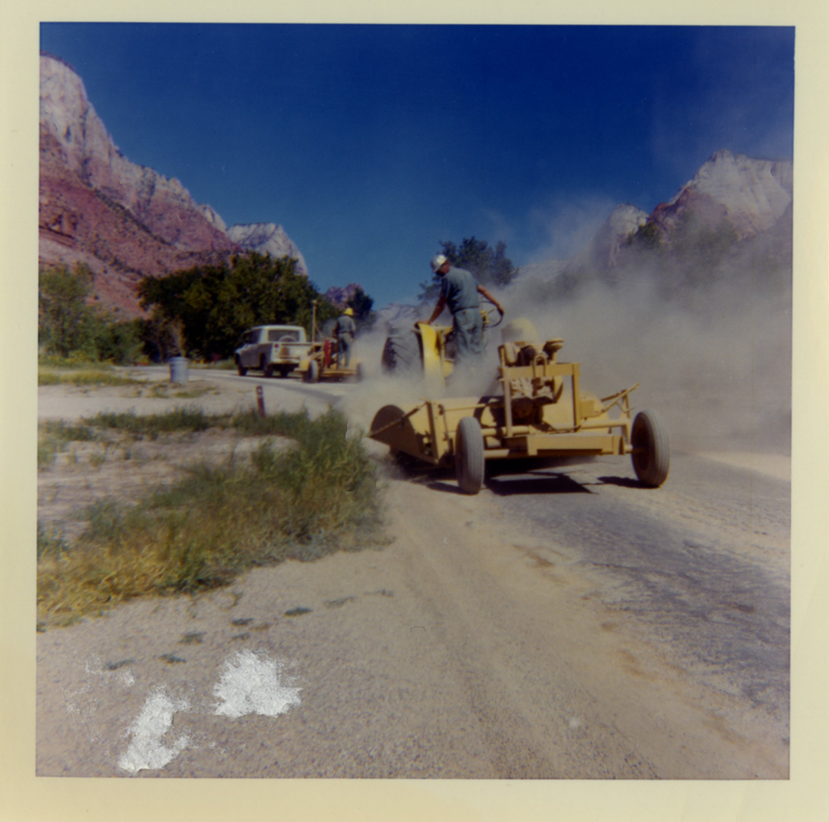 Men using chipseal machines to chipseal road.