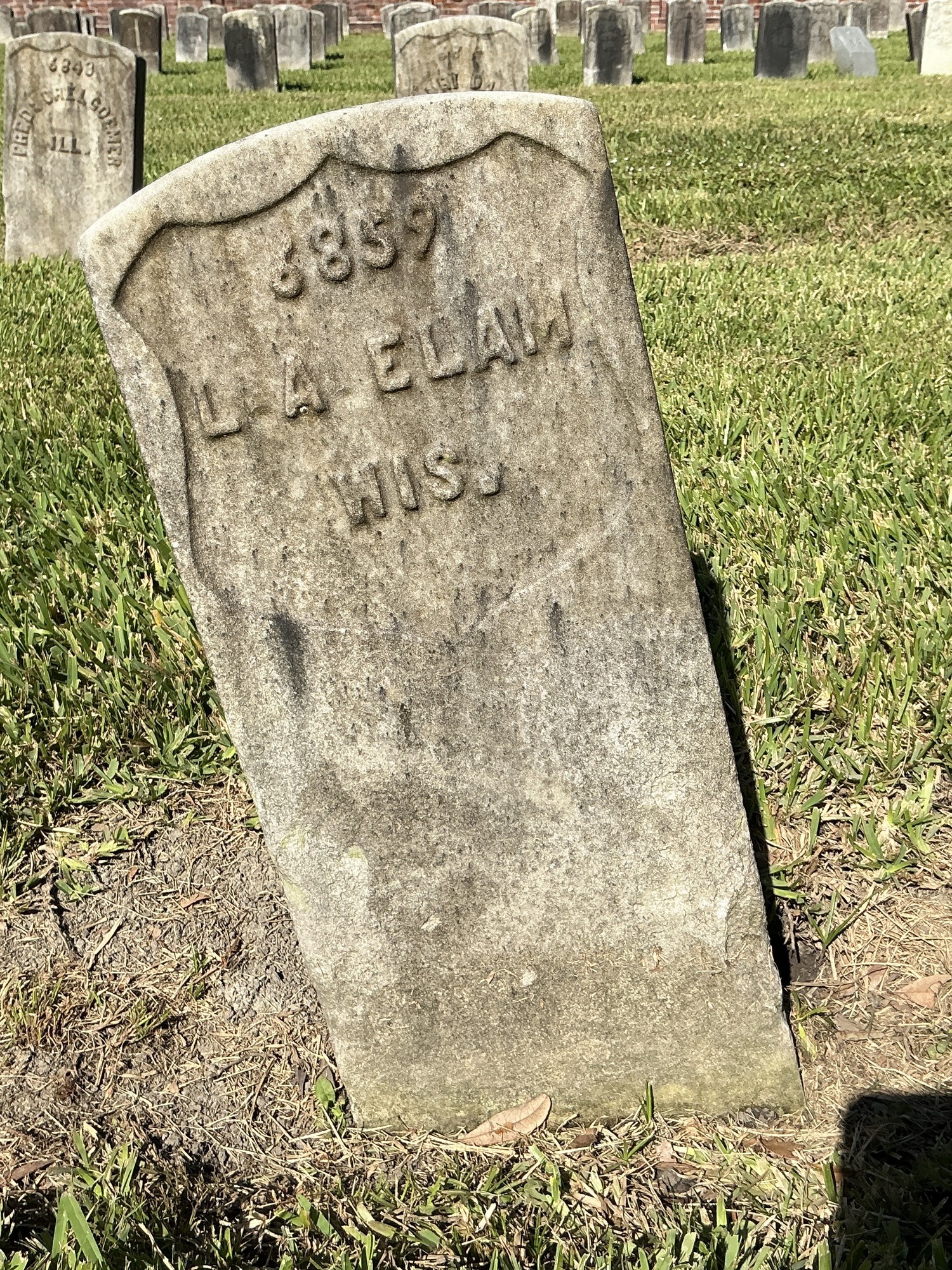 Front of historic upright marble headstone with recessed shield face.