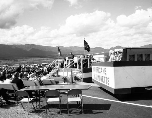 Warren F. Hamilton, Superintendent of Zion National Park, addressing visitors from podium at dedication of Taylor Creek road (Kolob Canyons). Note Hurricane Harmonetts [Harmonettes] singing group at right.