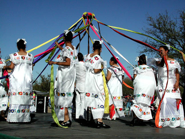 Folklórico dancers at La Fiesta de Tumacácori in white dresses with ribbons around a may pole