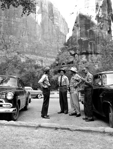 Four men standing in parking area at the Temple of Sinawava. Left to right: Assistant Superintendent Chester A. Thomas, Assistant Chief Ranger Fred R. Brueck, publisher Alfred A. Knopf, advertising agent C. Denhard.