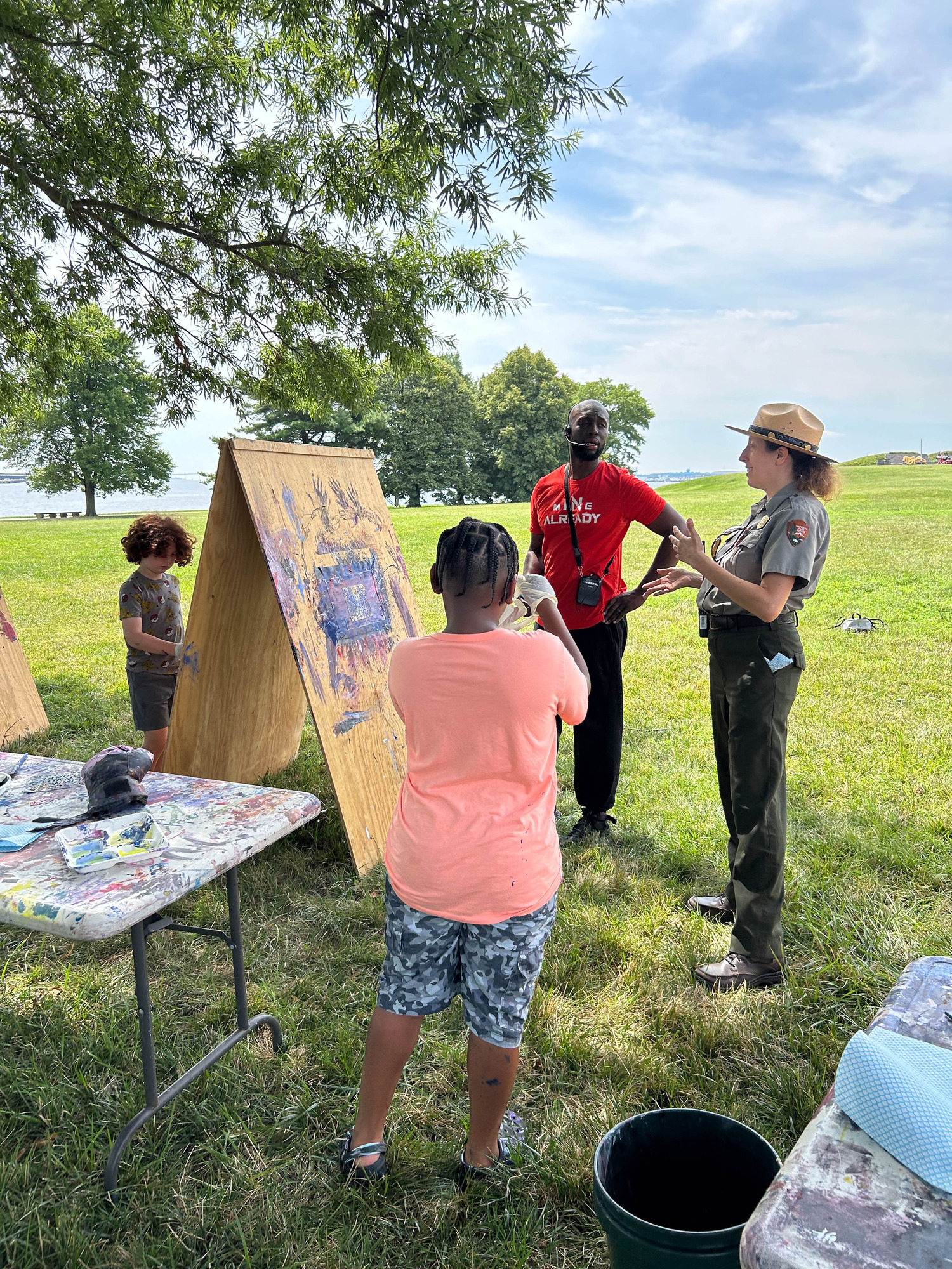Ranger Stephanie with camp staff, helping children with painting