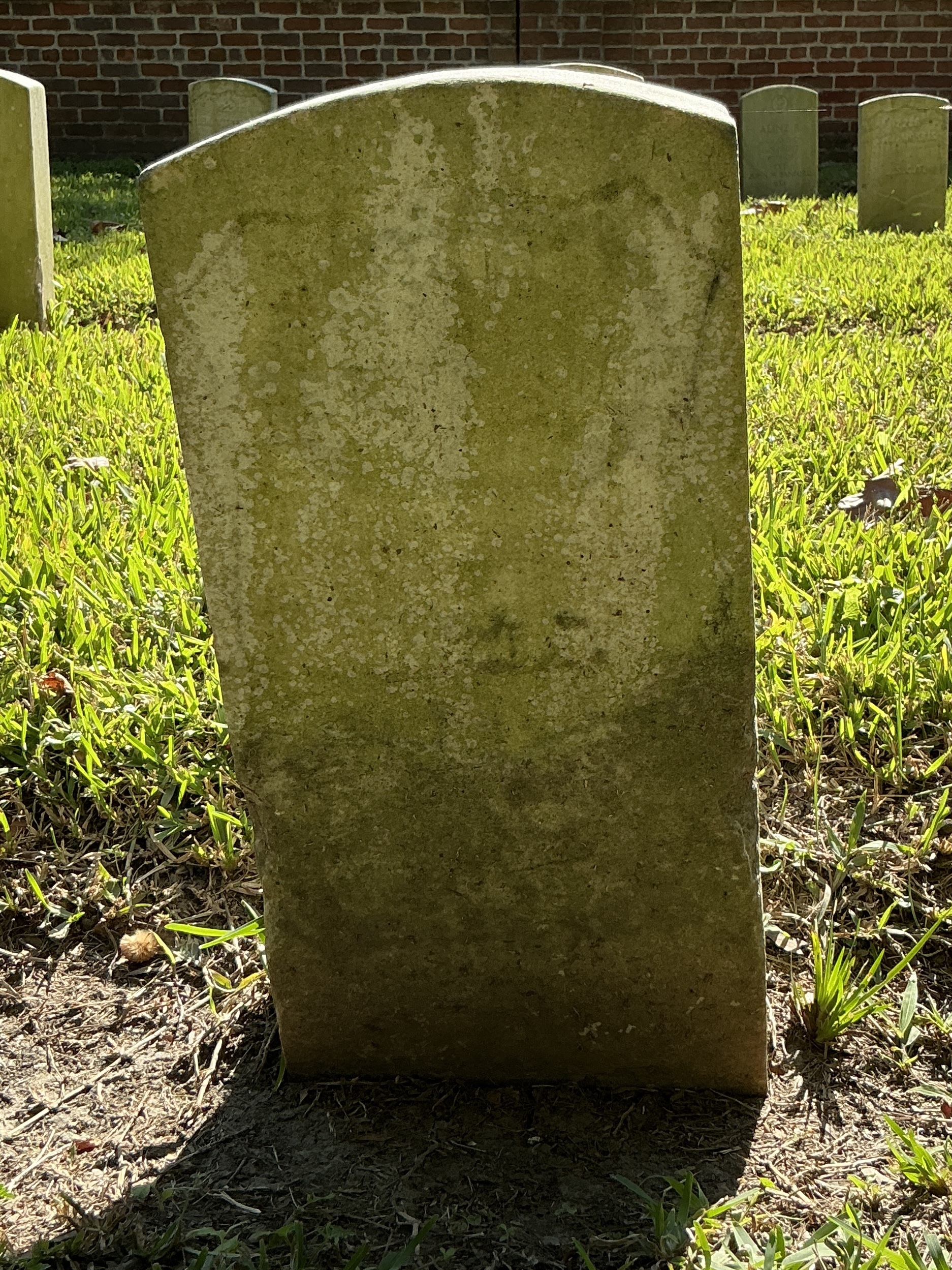 Front of historic upright marble headstone with recessed shield face.