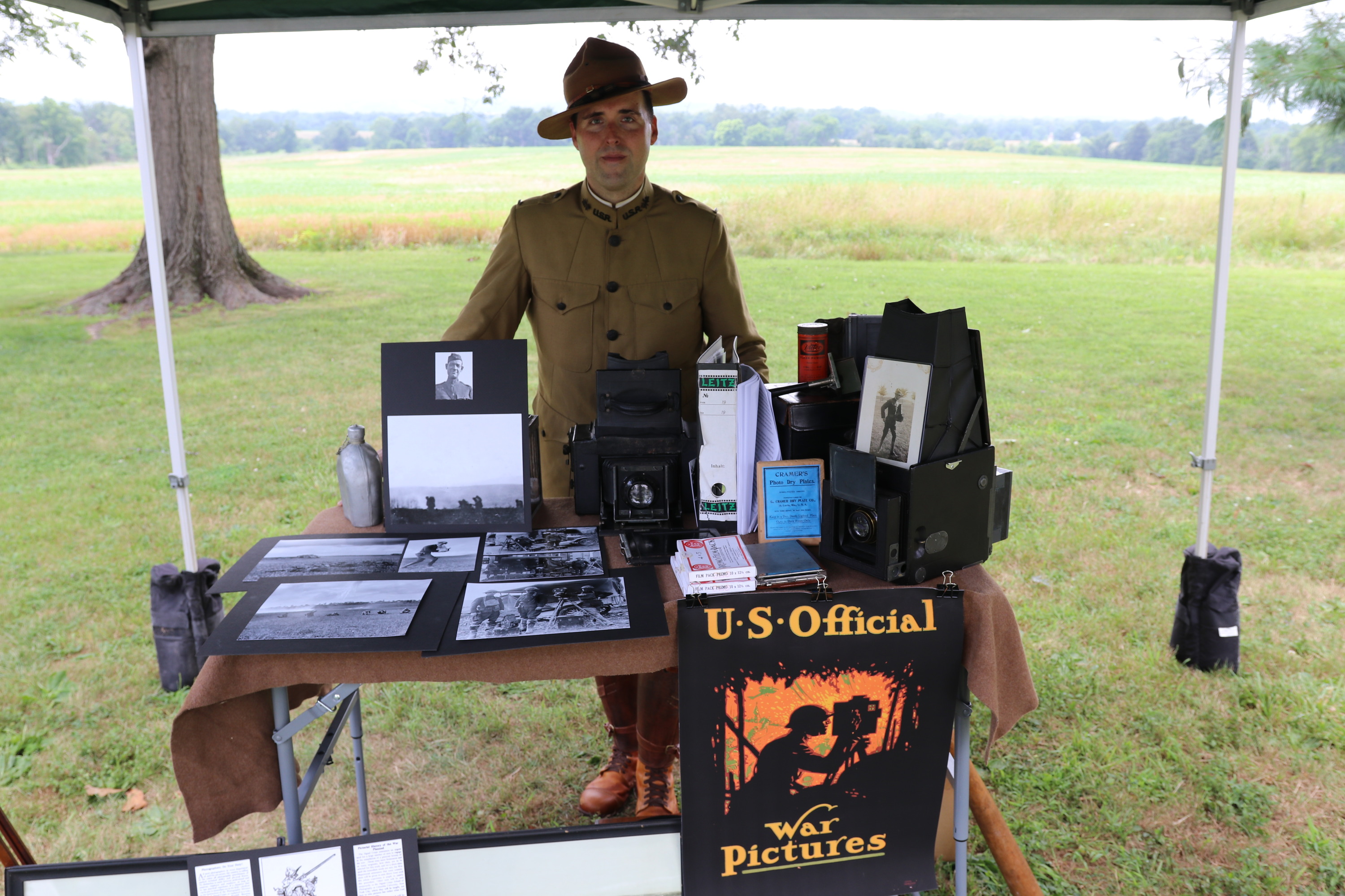 Living History volunteer Marc Hermann stands behind a table with a US Army photograph display