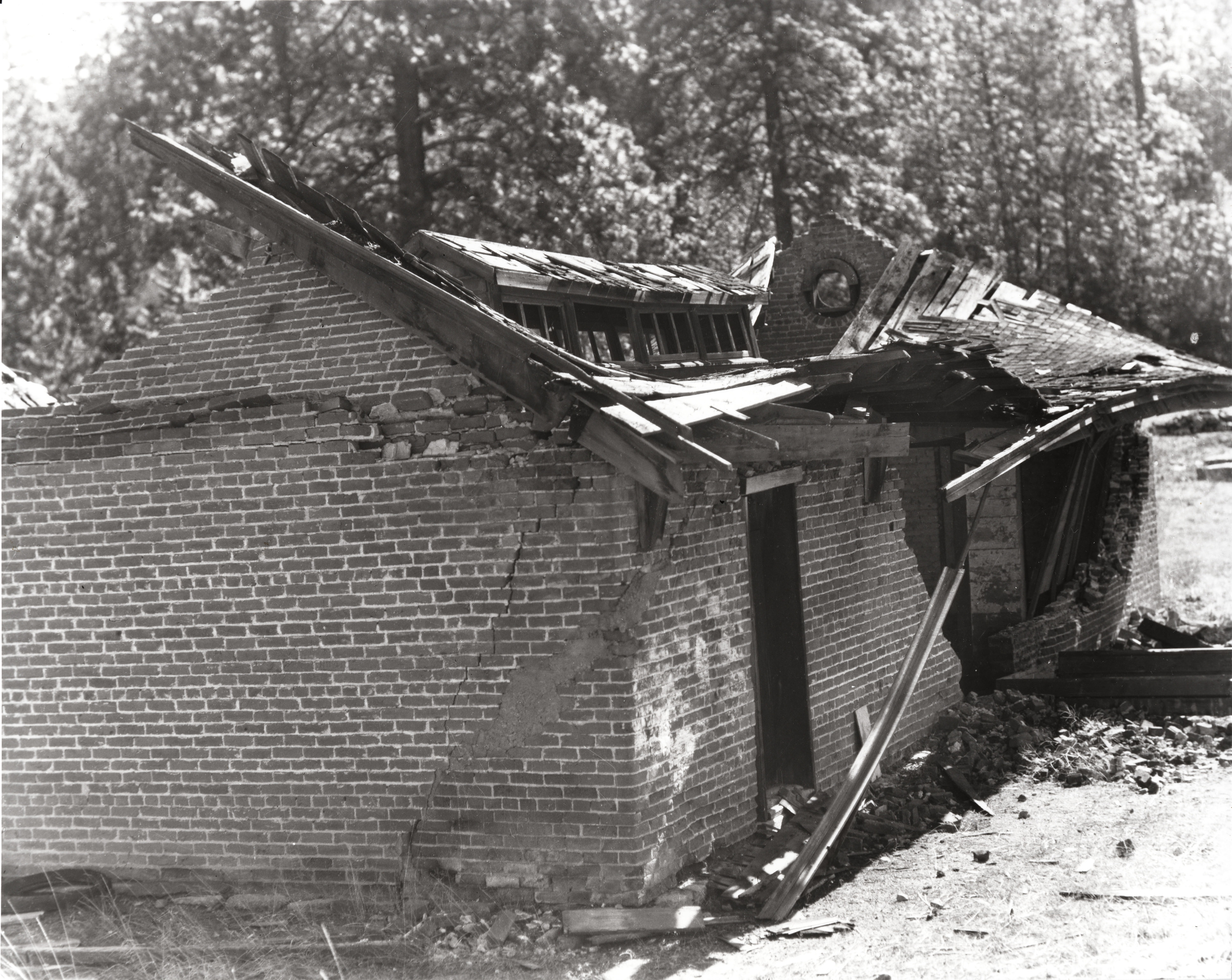 Black and white photo of a brick building with collapsed roof.