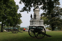 2 people sit on a monument featuring statues. There are three cannon 