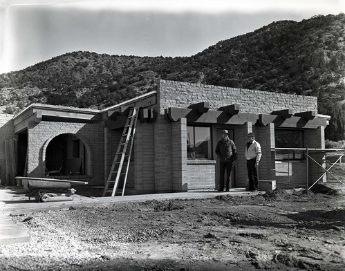 Two men standing next to scaffolding during construction of the Kolob Canyons Visitor Center.
