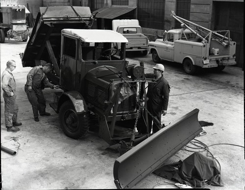Painting FWD snow plow in maintenance area.