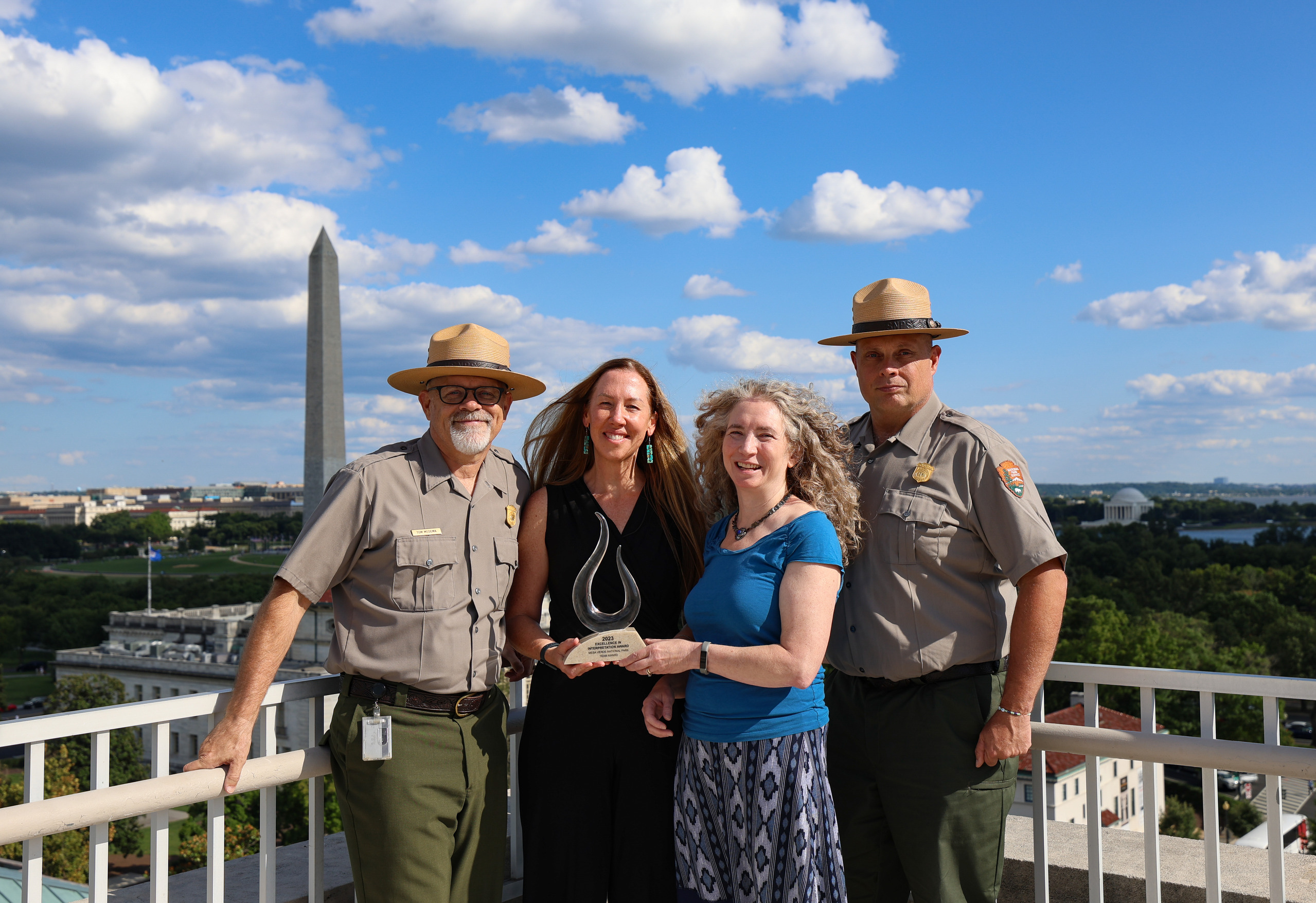 Two female award recipients and two other people pose for a photo on a rooftop.