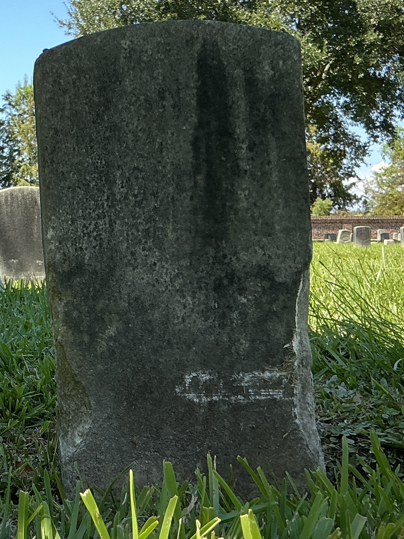 Back of historic upright marble headstone with recessed shield face.