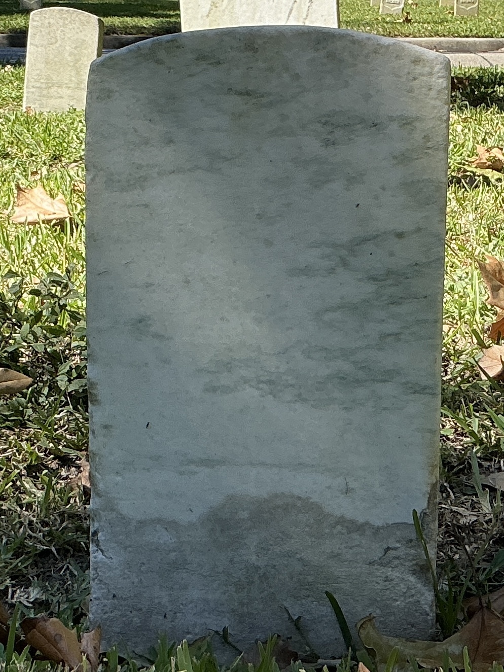 Back of historic upright marble headstone with recessed shield face.