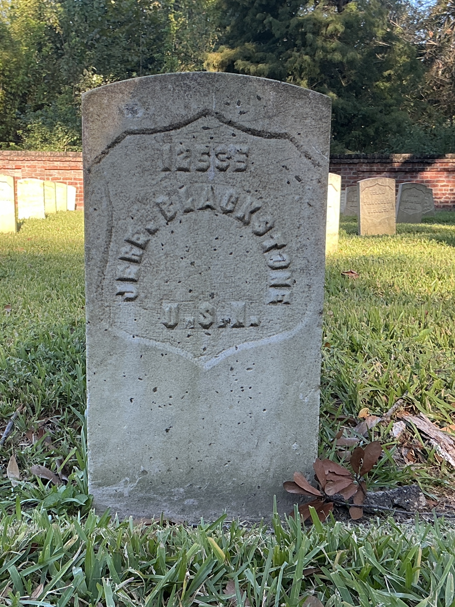 Front of historic upright marble headstone with recessed shield face.
