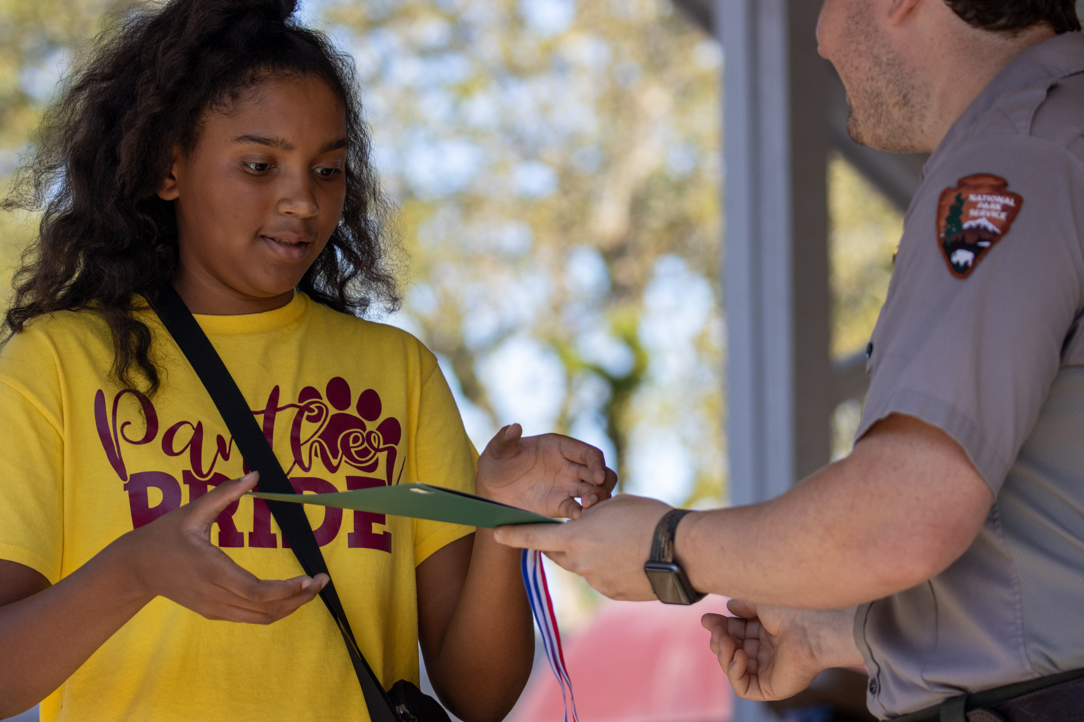 Young teen in yellow "Panther Pride" t-shirt receiving award during Plains Peanut Postcard Contest awards ceremony.