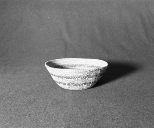 Marie Rozier Collection, Catalog No. 2-266. Object: Yokuts basket. Dimensions: 9 x 3 1/4". Materials: Willow root, redbud, grass bundle foundation. Technology: Interior work face, rightward coil direction, fag ends trimmed on work face, moving ends clipped or bound under. Collection History: No documentation, but identical to work produced by Blind Molly, a Yokuts of the Bakersfield area. Use of willow root in Yokuts baskets is quite uncommon. Photographed by Michael Dixon in December 1982. Catalogued by Craig Bates and Barbara Beroza. Yosemite Collections, National Park Service.