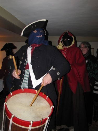 mummers enter the house with drums and shouts