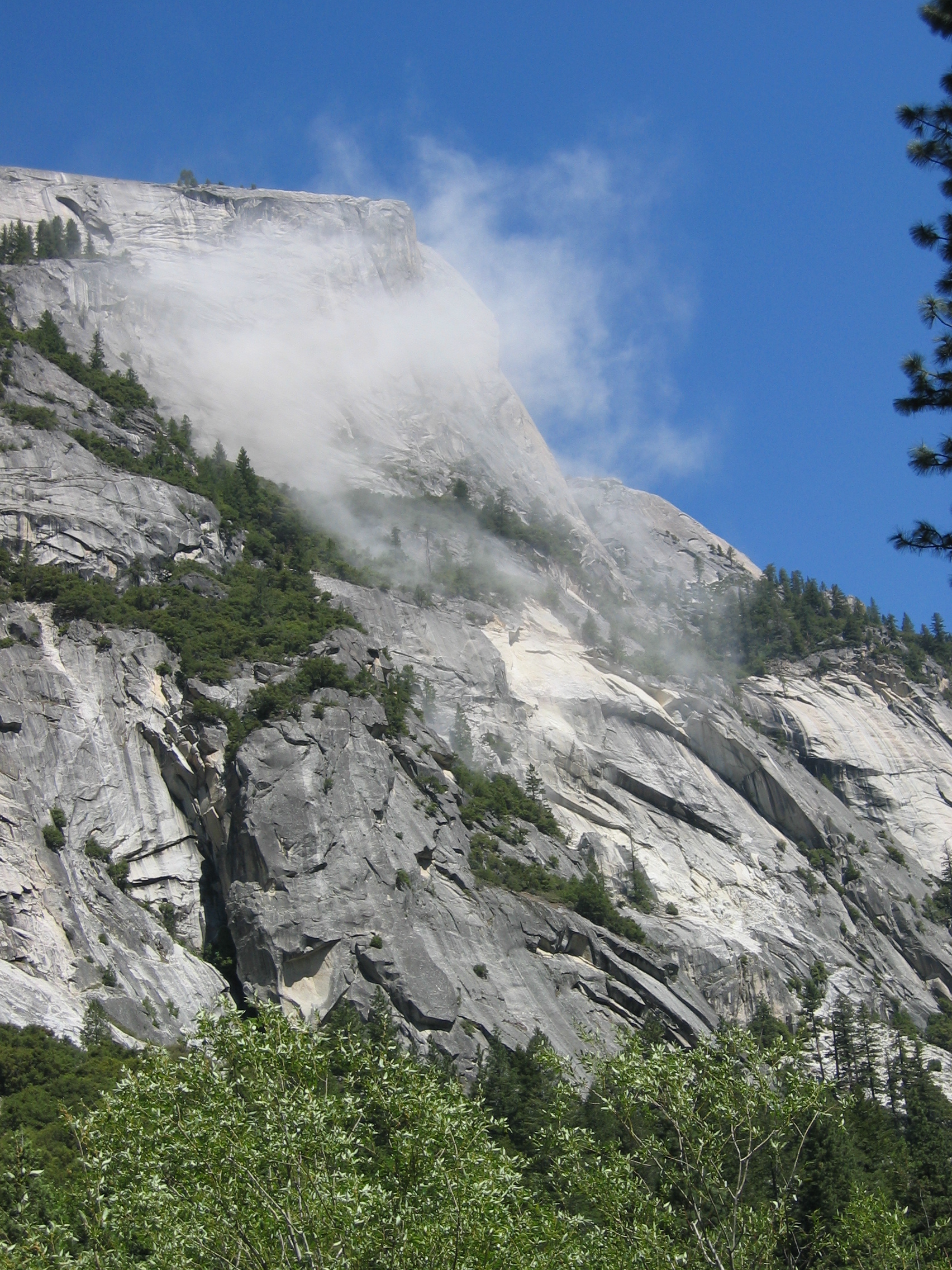 A thin, wispy dust cloud rises from a steep cliff.