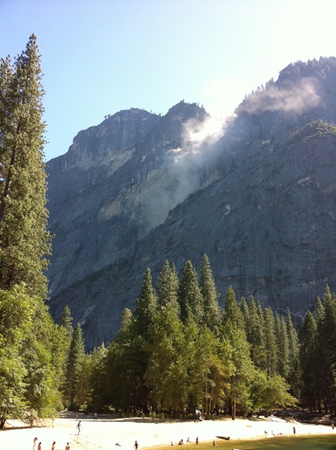A dust cloud rises from an angled ledge on the middle of a steep cliff.