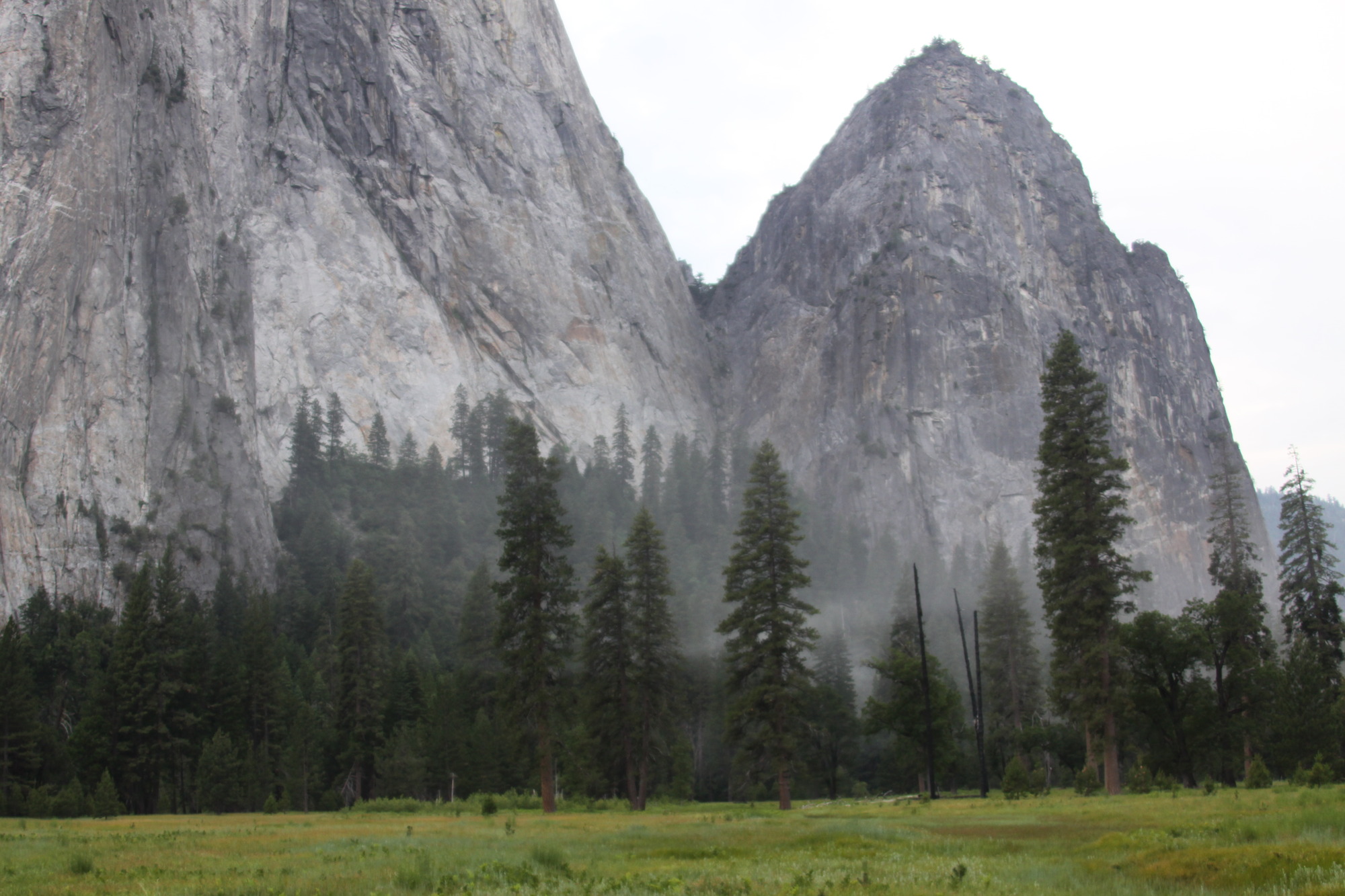 A small dust cloud dissipating near the base of a steep rock cliff.