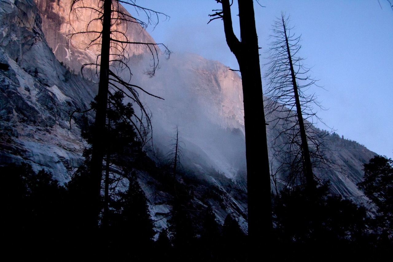 A dust cloud rising up the lower part of the Northwest Face of Half Dome in the evening light.