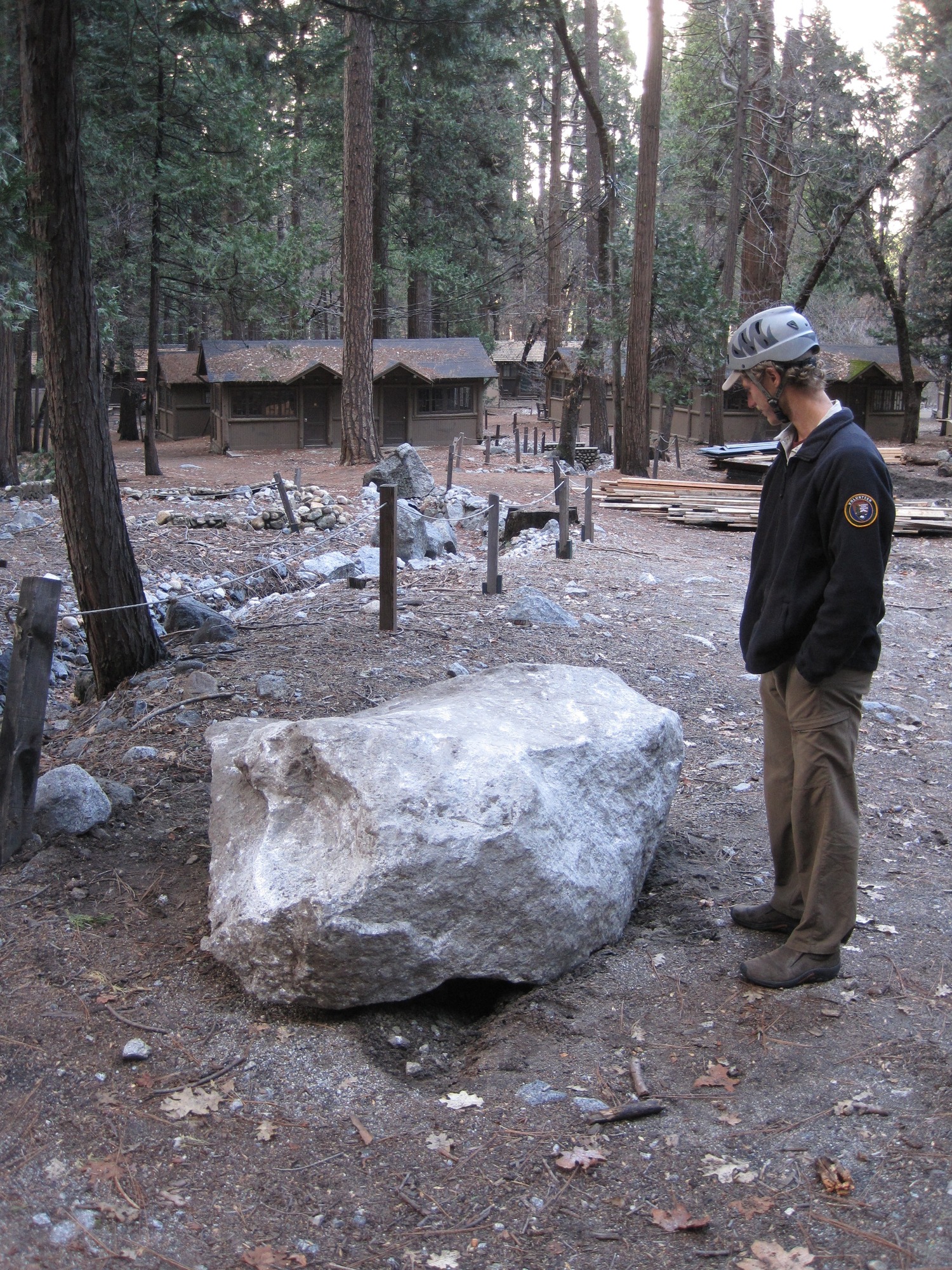 Person standing by a fresh boulder in the Curry Village Residential Area.