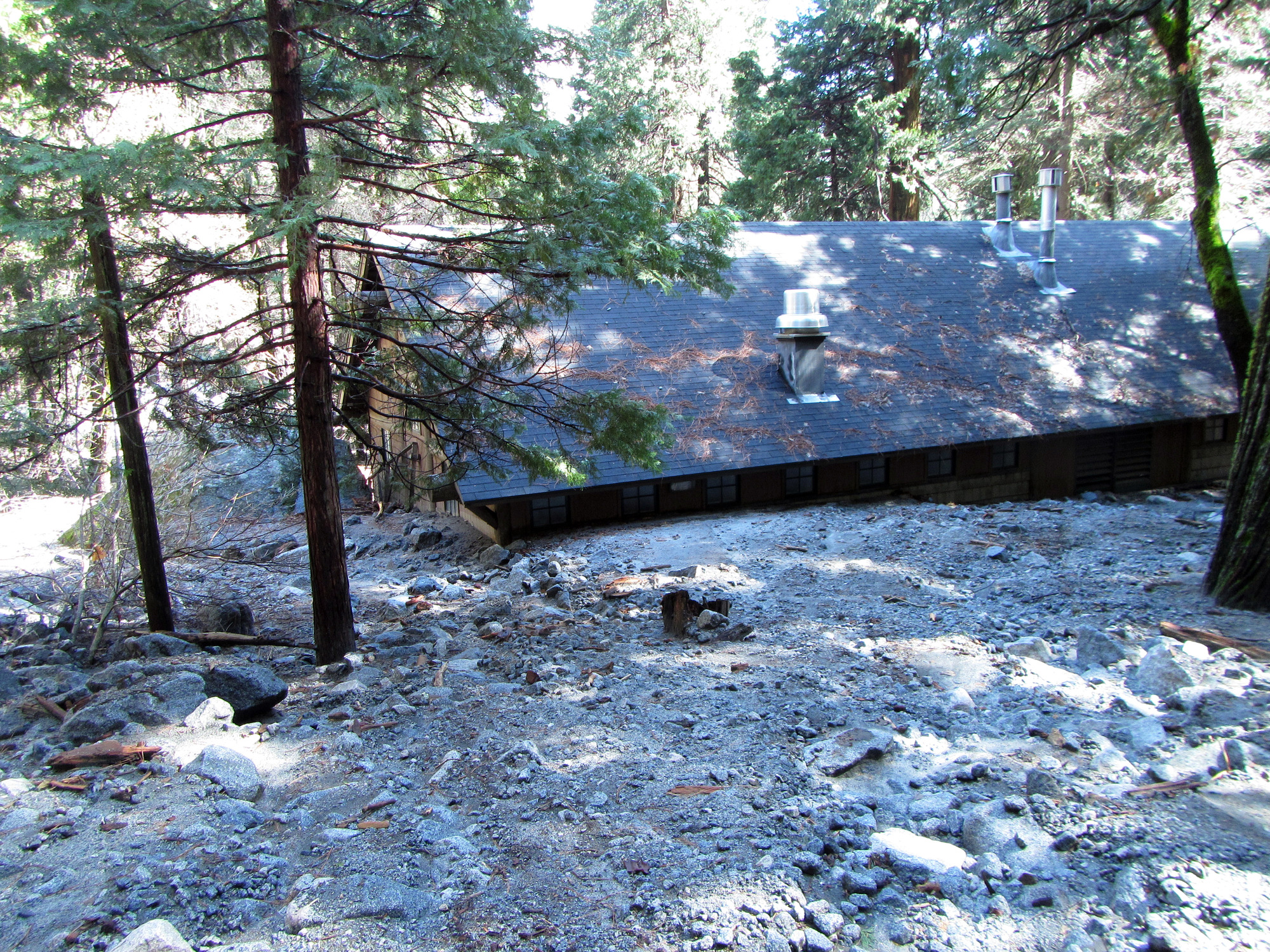 The uphill side of a building buried to its eaves with sand, gravel, and cobbles.