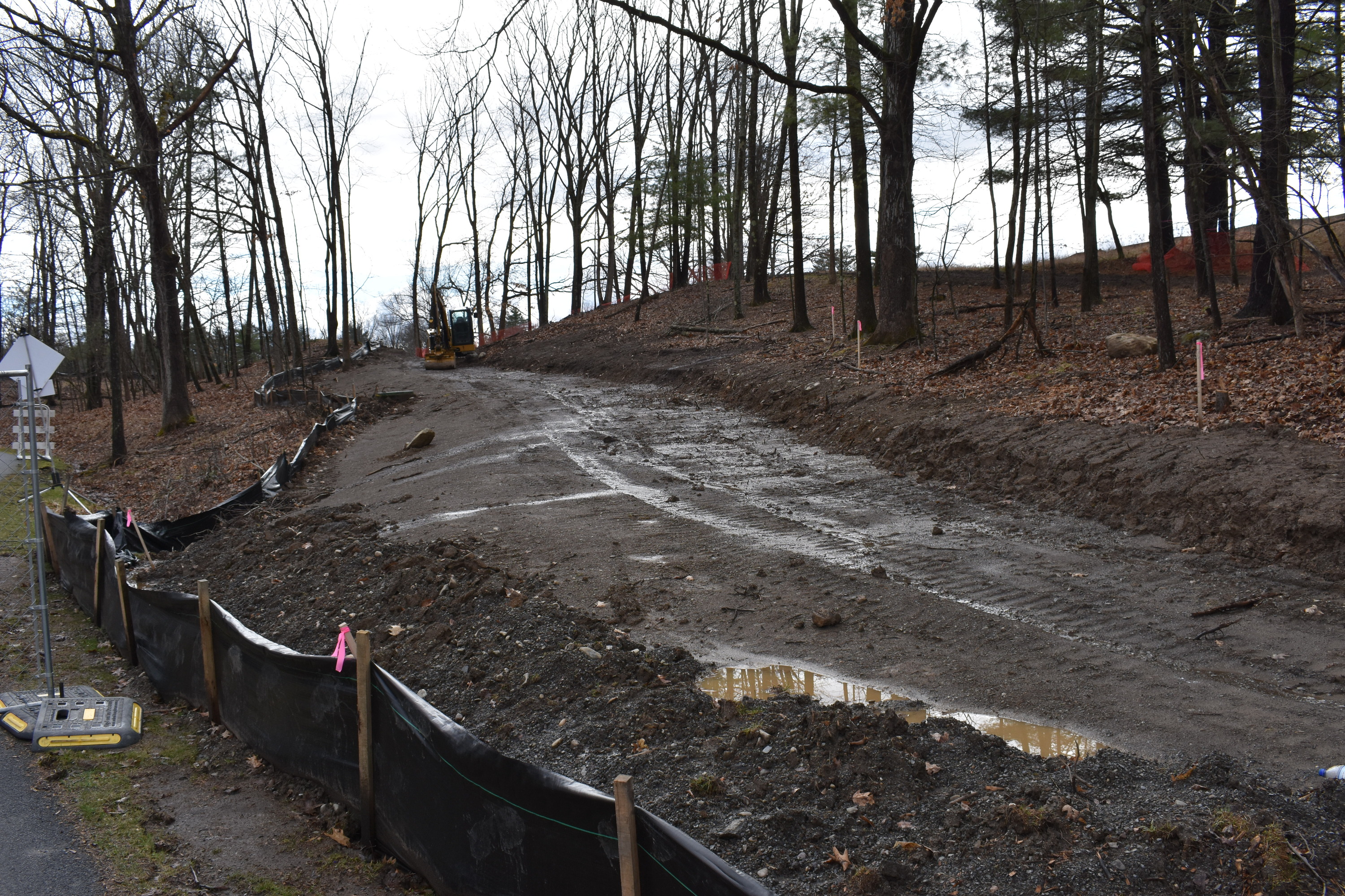 A muddy patch goes uphill from right to left. Construction equipment sits on the path in the distance.