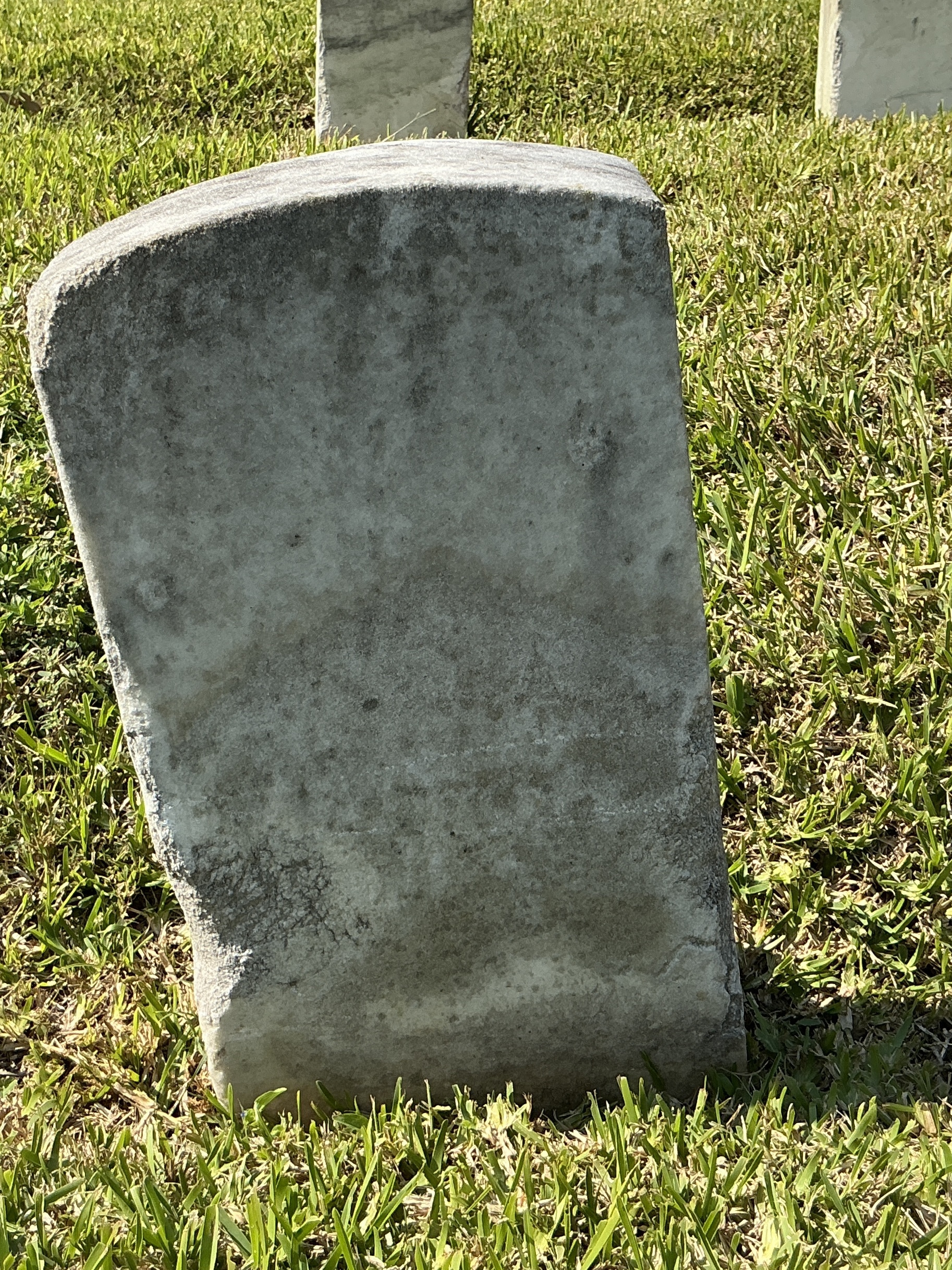 Back of historic upright marble headstone with recessed shield with recessed lettering face.