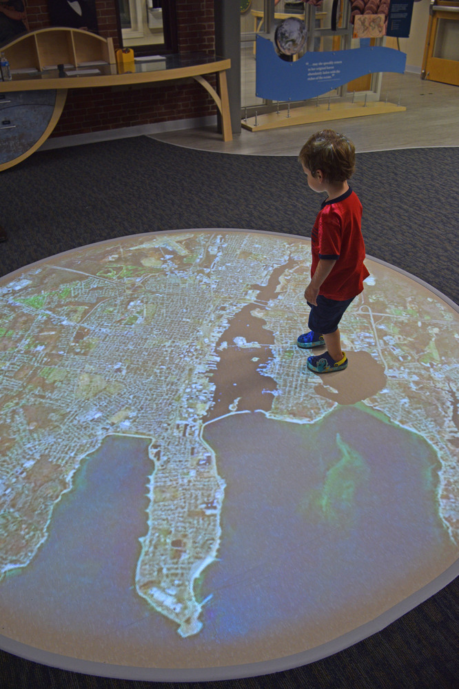 Young boy stands on floor map. 
