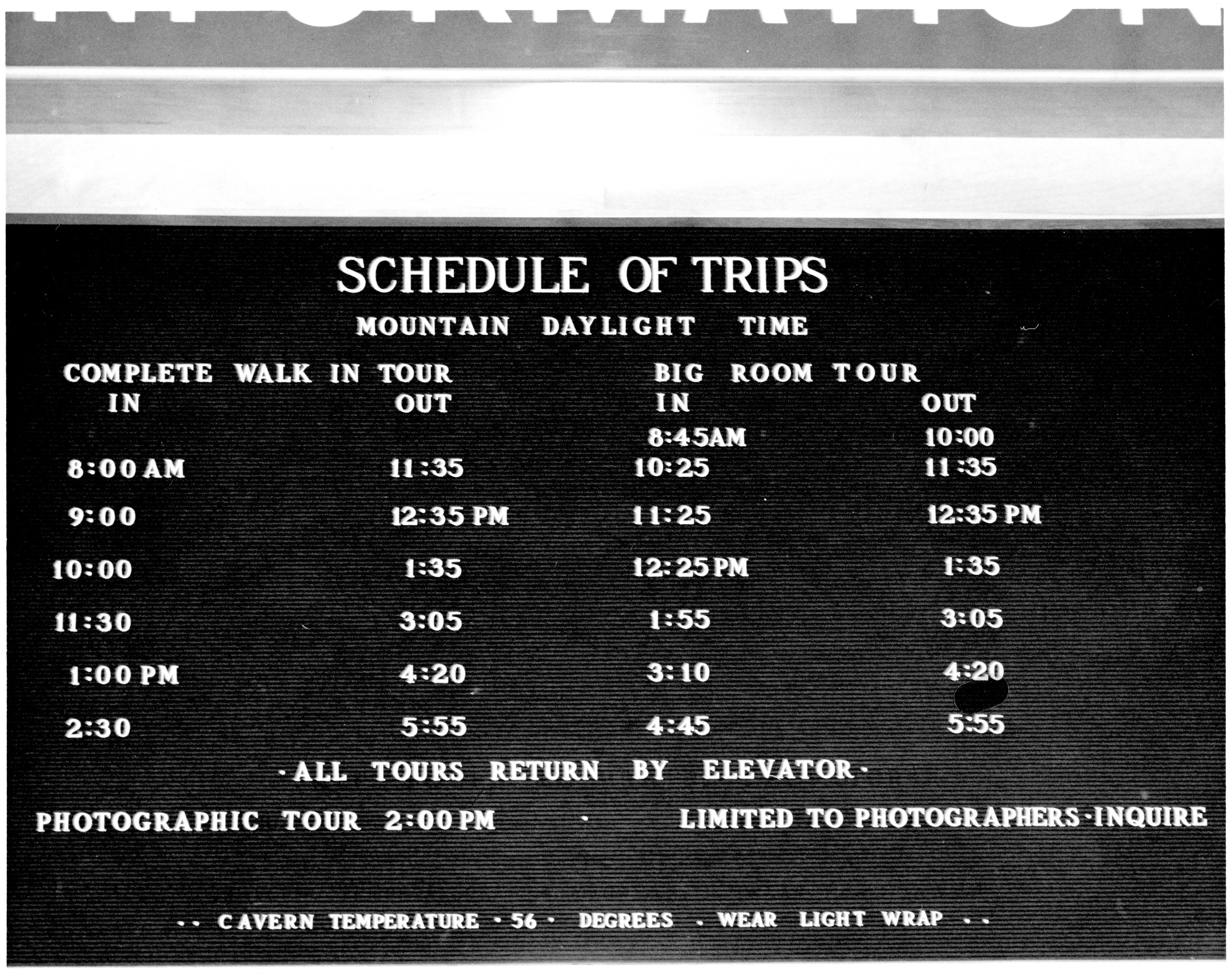 A black and white photograph of a board informing visitors of the schedule of trips.