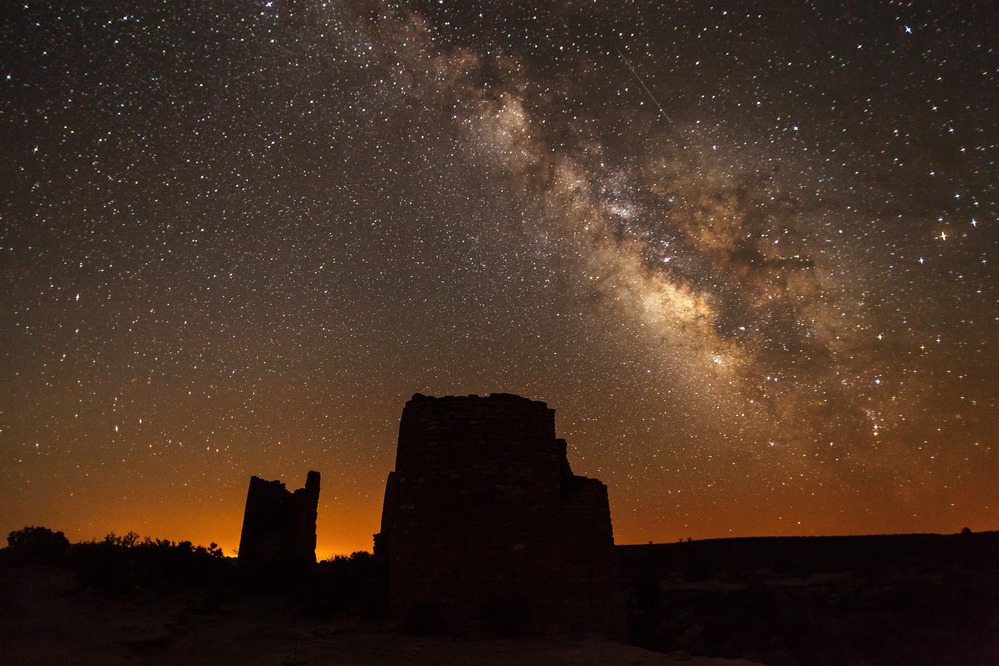 The Milky Way arcs above the silhouetted structures.