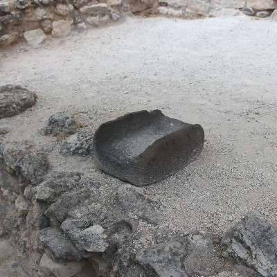 a large, rectangular black basalt rock with a deep trough carved into it
