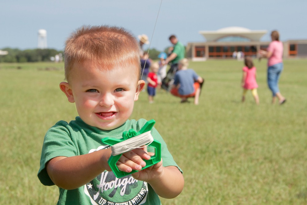 Young boy smiles as he flies a kite