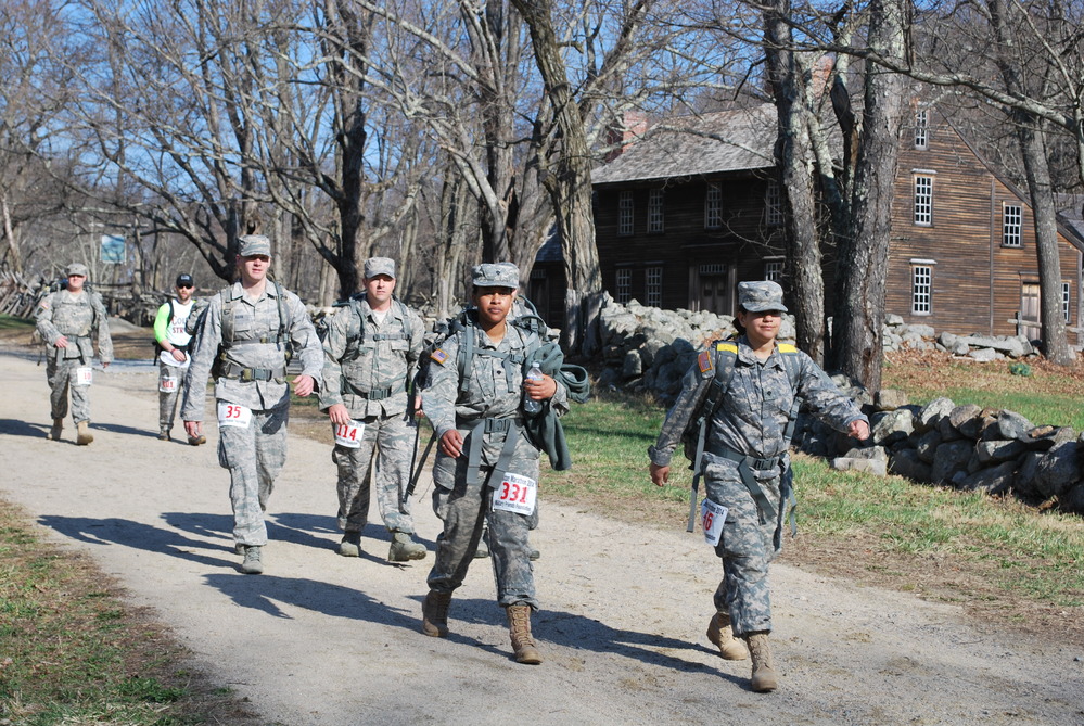 Modern-day American soldiers march past the home of two Revolutionary War soldiers.