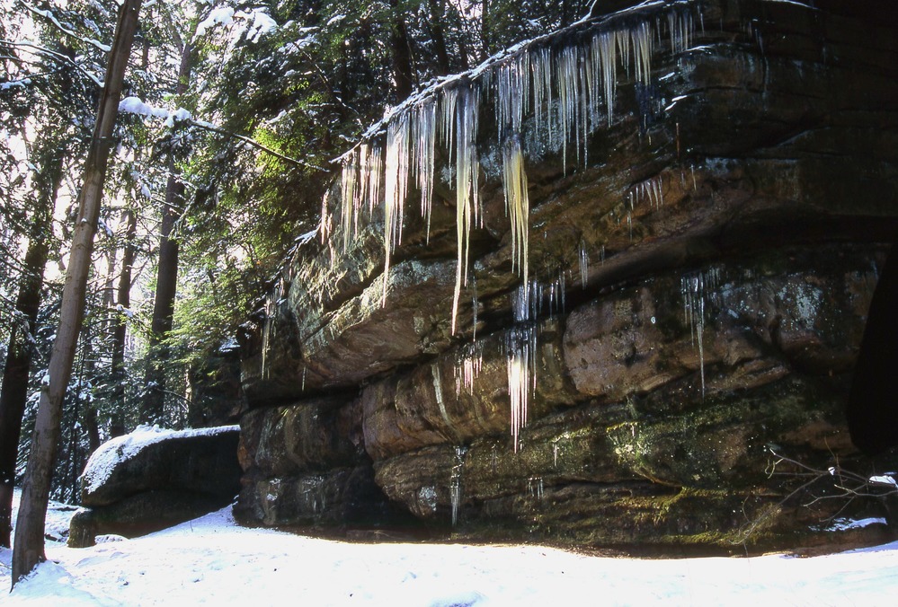 Snow and icicles hang from the sandstone ledges
