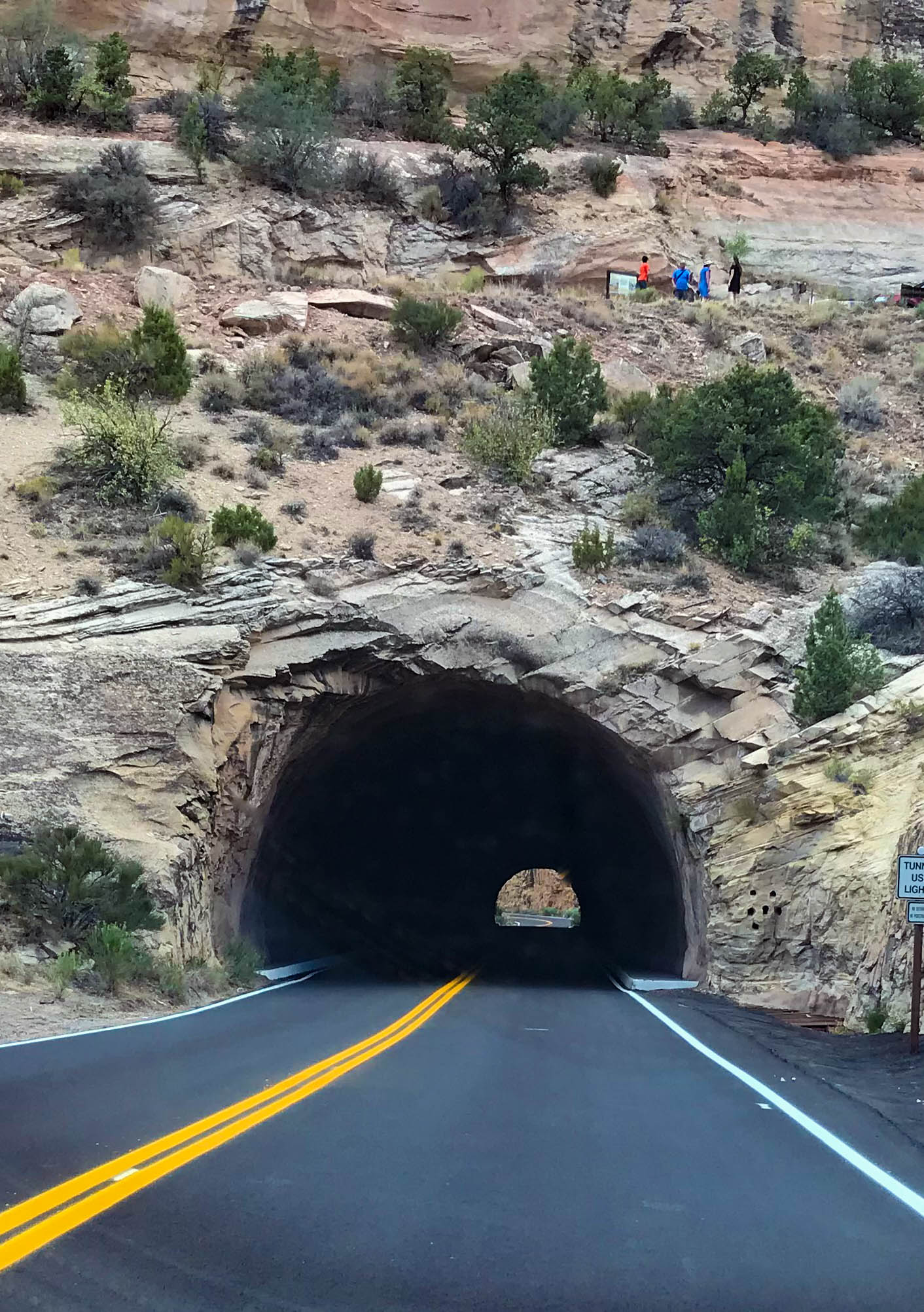 Visitors above a tunnel through a rock wall