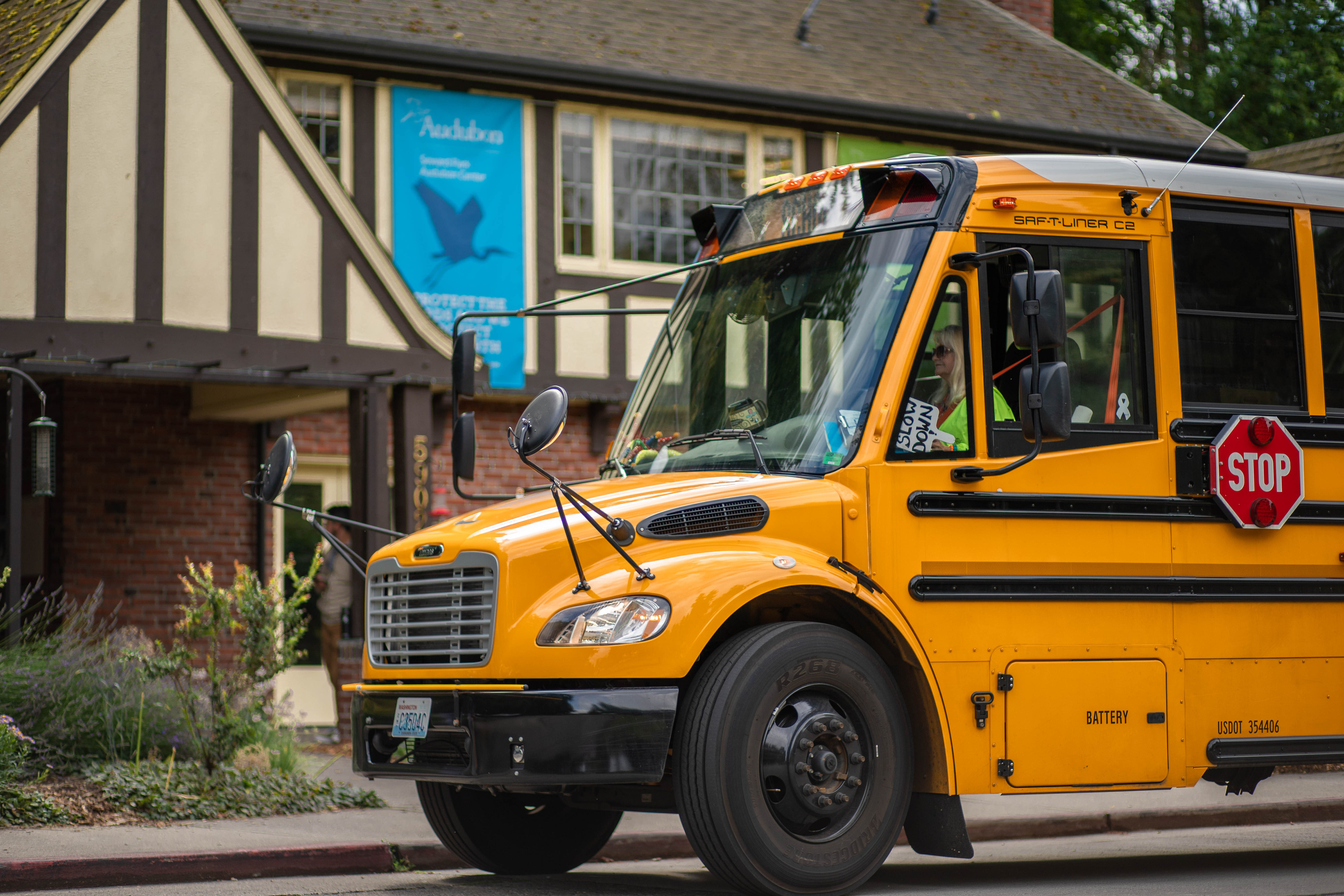Yellow school bus pulls up to Tudor-style park visitor center.