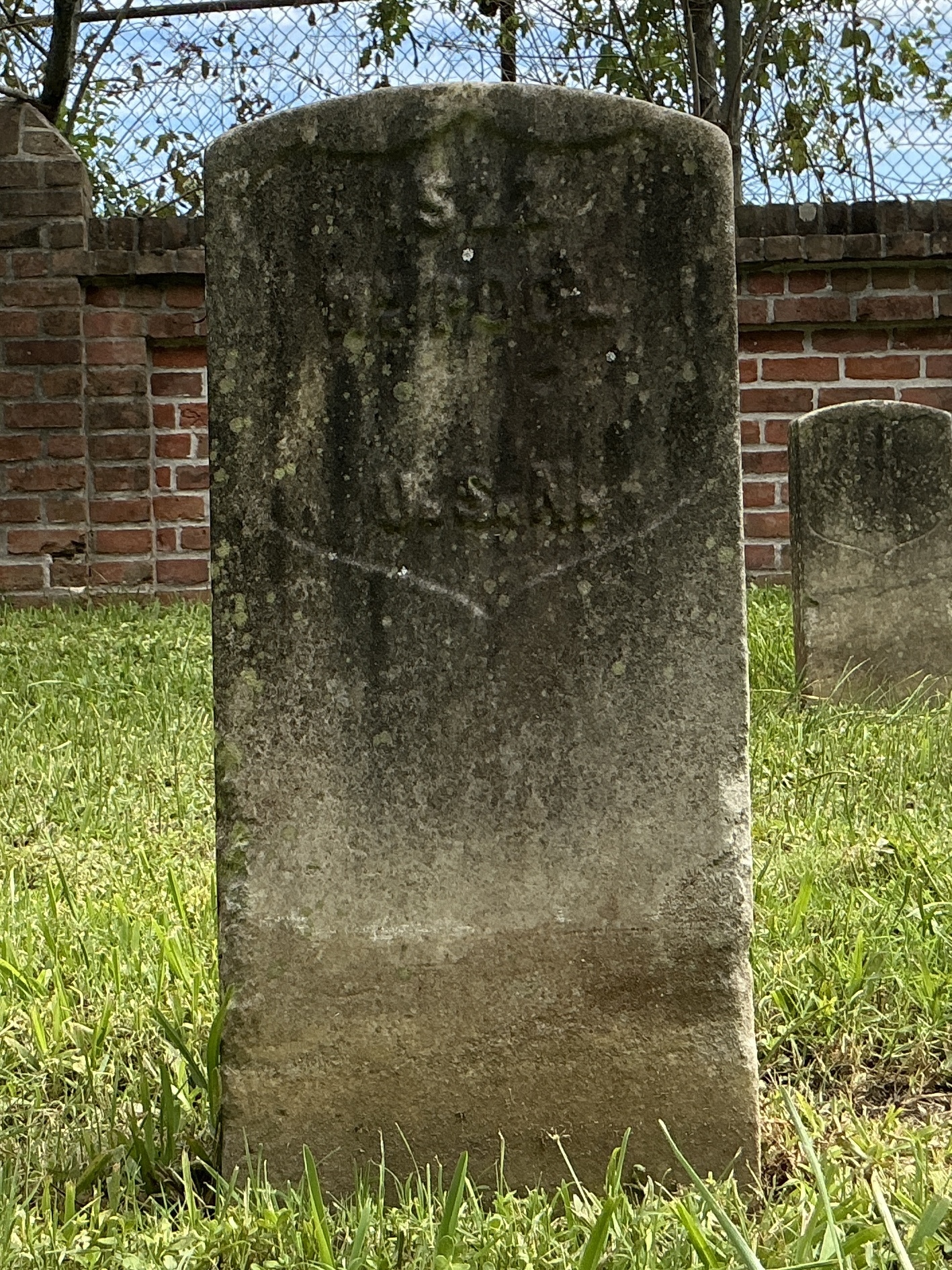 Front of historic upright marble headstone with recessed shield face.