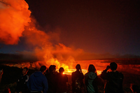 Group of visitors viewing an eruption at night. 