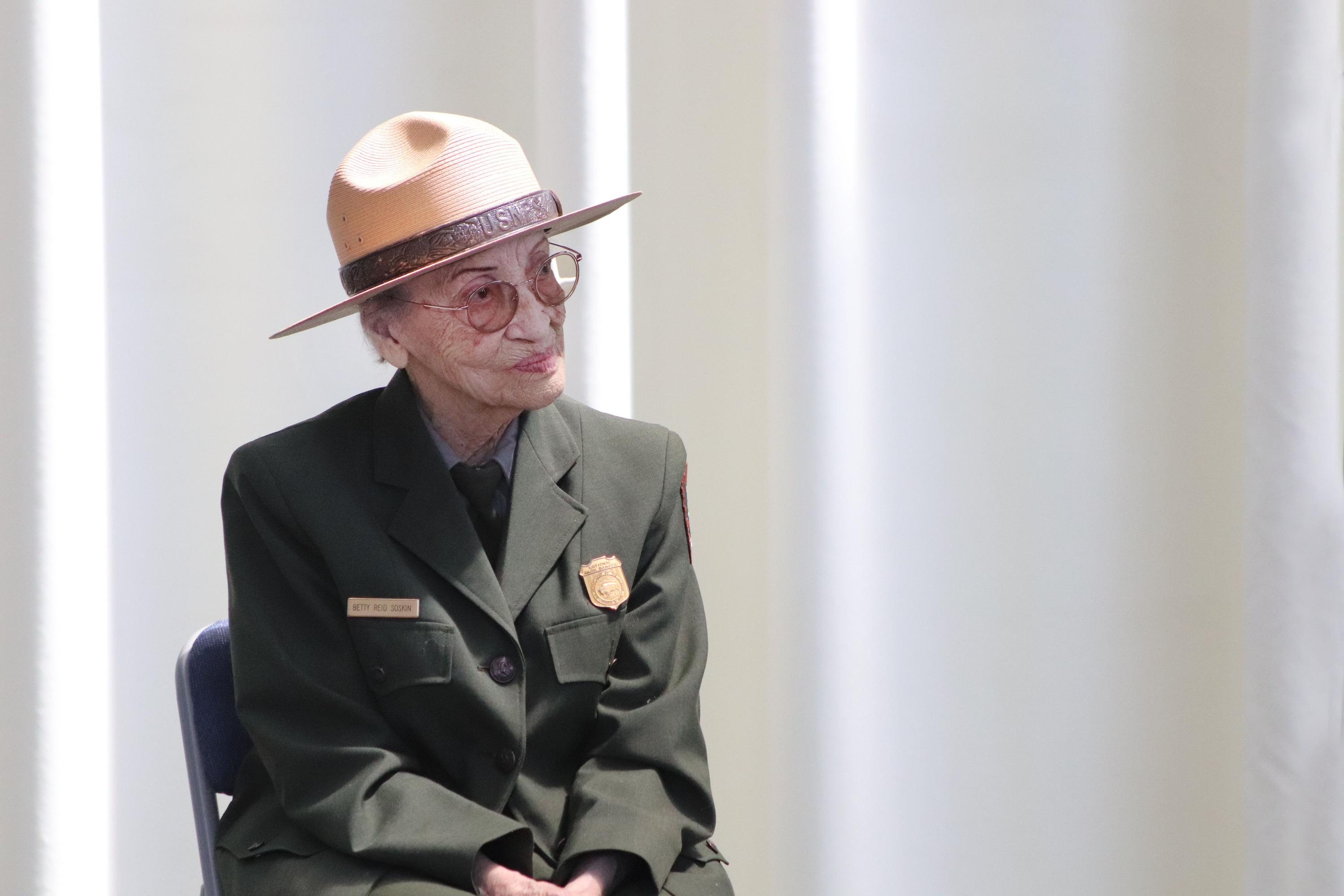A senior African American woman in a ranger uniform sits in a chair on stage. 