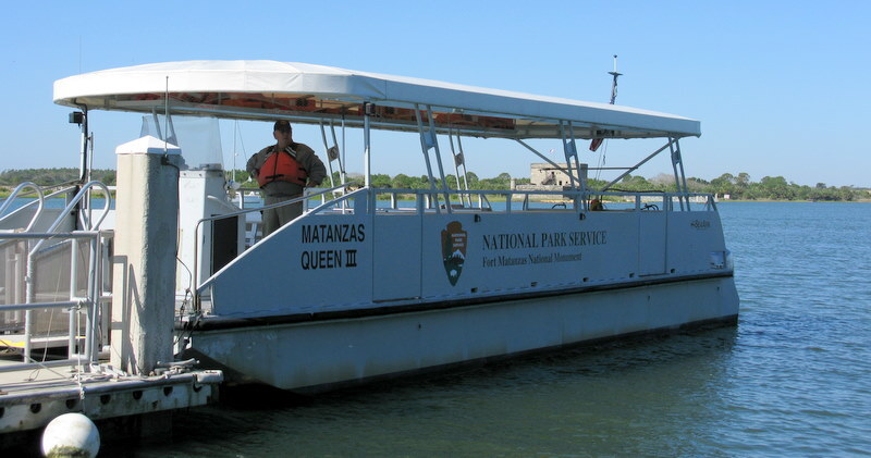 large metal pontoon boat with canopy.  Boat name and National Park Service written big on the side. 